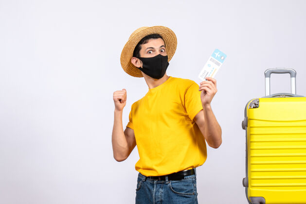 男性正面图身穿黄色t恤的男性游客站在黄色手提箱旁举着旅行票肖像人站立