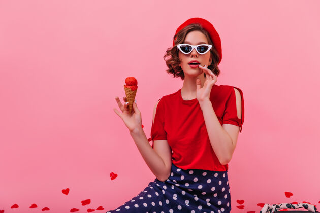 心烦戴着优雅太阳镜的快乐白人女孩在吃冰淇淋美丽的法国女模特在享受冷甜点正面粉色模特