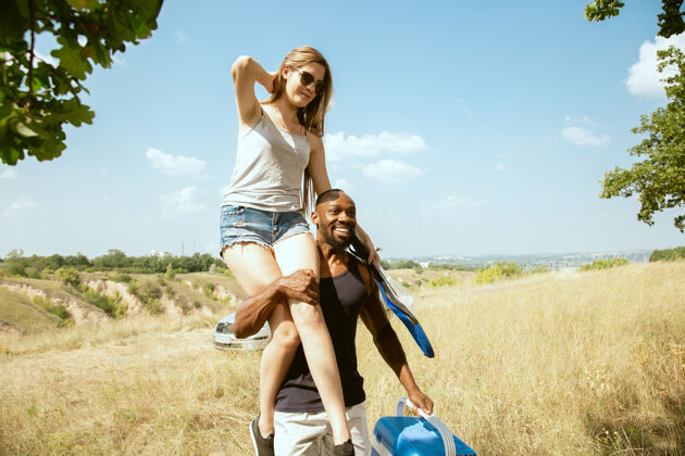 人在阳光明媚的夏日 一对年轻的多民族国际浪漫情侣在户外的草地上非洲裔美国人和白人妇女一起野餐关系的概念 夏天使用举行草地