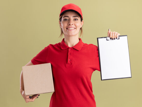 橄榄微笑着的年轻漂亮的女送货员穿着制服拿着剪贴板和名片盒在橄榄绿漂亮人成人