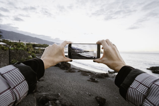 天空一个女人通过他的手机拍摄大海的画面背景美丽电话