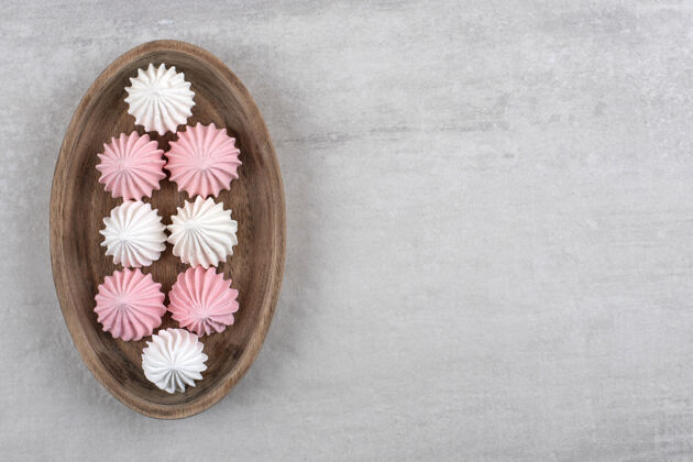 糕点石头桌上放着一盘白色和粉色的酥皮糖自制小吃茶碟