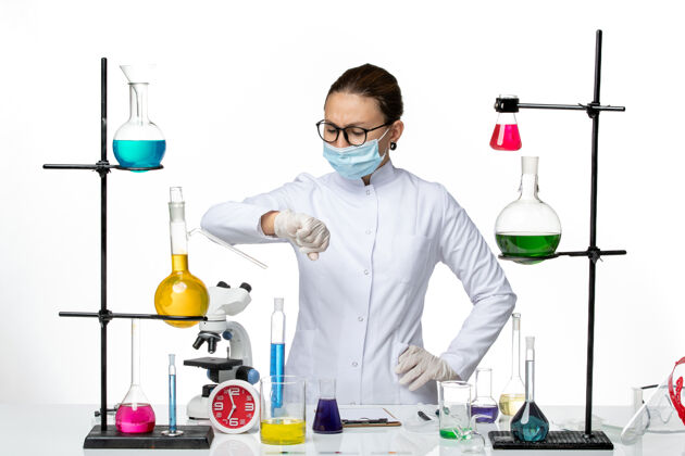 化学前视图身穿医疗服的女化学家戴着口罩看着她手腕上白色背景的病毒化学实验室covid-飞溅医学飞溅医生