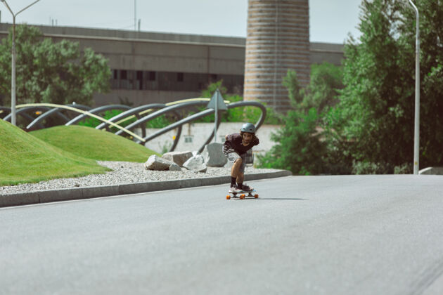 滑板公园在阳光明媚的日子里 在城市街道上玩滑板的人穿着装备的年轻人在沥青路面上骑行和玩长板休闲活动 运动 极限 爱好和运动的概念锻炼男孩溜冰者