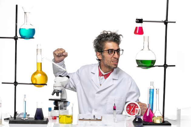 西装前视图穿着医疗服的男科学家坐在桌子前 白色背景上的解决方案可维实验室病毒健康化学病毒桌子化学