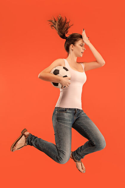 成人向胜利前进年轻女子像足球运动员一样跳着踢着球向前女健身