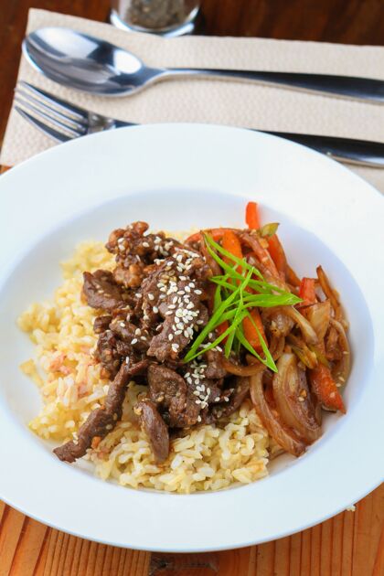 饮食白盘子里有米饭 肉 蔬菜和调味料 旁边还有勺子和叉子配料烹饪文化