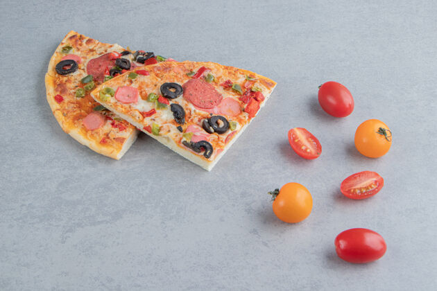 切片一小包西红柿和披萨片放在大理石上垃圾食品午餐晚餐