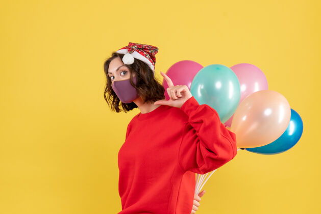人正面图年轻女性隐藏在无菌面具气球颜色节日情感新年圣诞女人年轻女性前面黄色