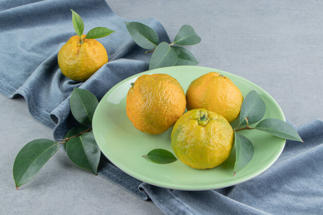 风味橘子和叶子放在大理石上的一块布上饮食橘子美味