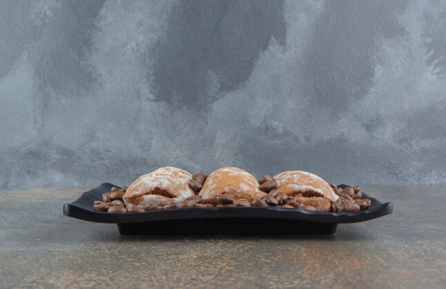 美味咖啡豆和饼干放在一个黑盘子里烘焙糕点风味