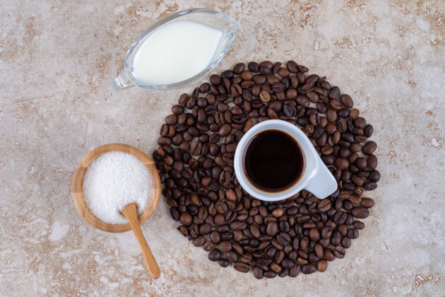美味小碗糖旁边有一堆咖啡豆围着一杯咖啡糖排列