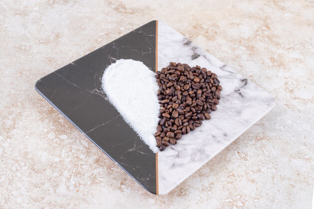 美味糖和咖啡豆在大理石板上排列成心形糖芳香豆