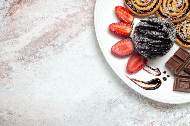 美食俯瞰美味饼干与巧克力蛋糕和草莓在白色空间生的茶饼干