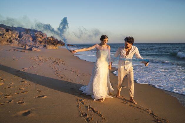 自然一对美丽的情侣在海滩上与蓝色烟雾弹合影的照片情人海洋海岸