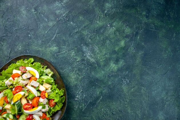 晚餐半张自制的美味沙拉在一个黑色的盘子里 在绿黑色混合色背景上 有自由空间沙拉壁板混合