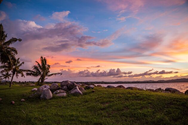 日落美丽的拍摄日落在海滩与草和棕榈树多云海景海洋