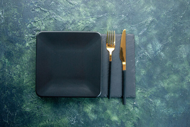 餐具顶视图黑色方形板与金色刀叉上的深色背景色食品餐厅餐具晚餐厨房晚餐顶部食物