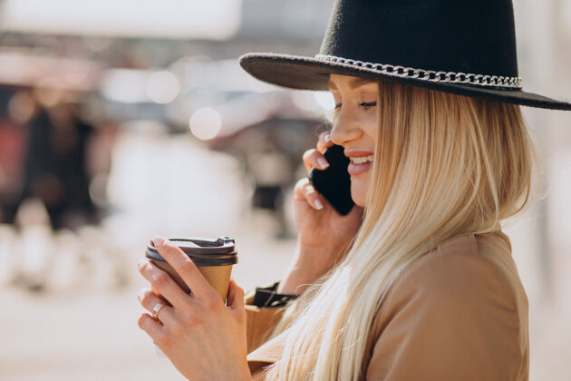 女性一个金发戴黑帽子的年轻女人在打电话喝咖啡城市优雅现代