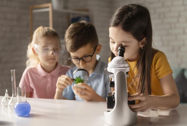 教育中等身材的孩子们在桌子旁工作显微镜科学科学