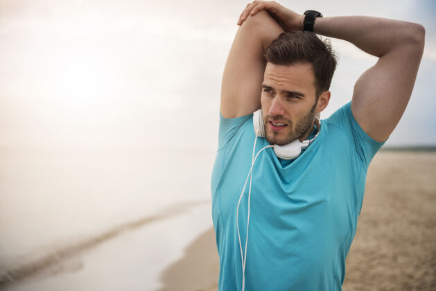 沙滩特写在海边慢跑的健康年轻人准备运动训练耳机