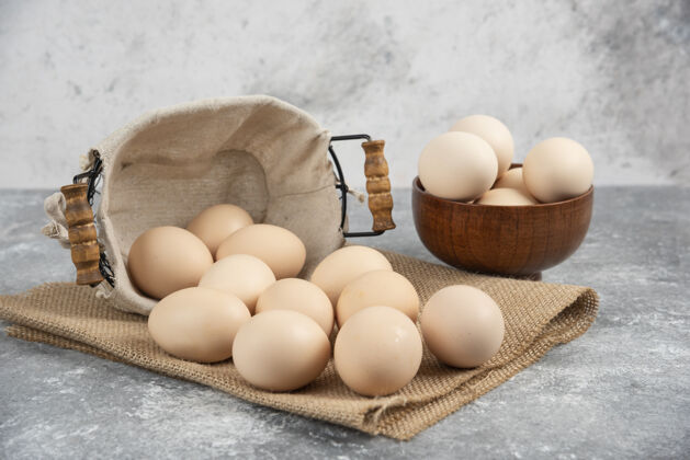 堆一篮一碗的有机新鲜生鸡蛋放在大理石表面上碗木头好吃
