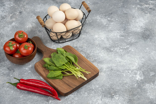 胡椒柳条篮子的生有机鸡蛋和新鲜蔬菜放在大理石上鸡肉辣椒蔬菜