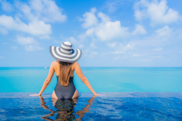帽子肖像美丽的亚洲年轻女子放松微笑休闲周围的室外游泳池在度假酒店海景年轻人女性放松