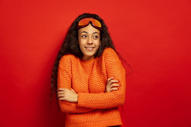眼镜以红色工作室为背景 黑色皮肤的非洲裔美国年轻女子的滑雪面具肖像人类情感的概念 面部表情 销售 广告 冬季运动和假日微笑 看侧面成人人黑发
