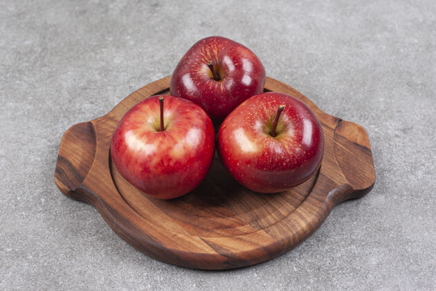 生的三个红苹果在木板上零食成熟的天然