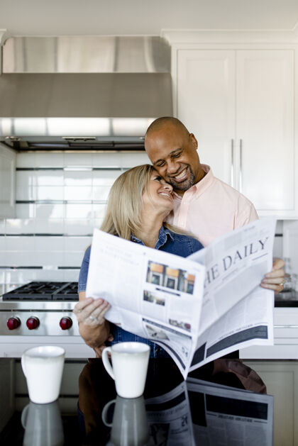 花时间幸福的夫妻一起在厨房看报纸混血儿浪漫浪漫