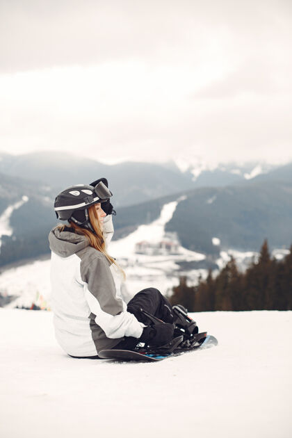 运动服穿着滑雪板套装的女人在山上手拿滑雪板的运动员在地平线上关于运动的概念娱乐女孩板
