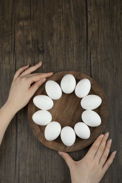 鸡女人的手拿着木板 木板上放着生鸡蛋膳食营养新鲜