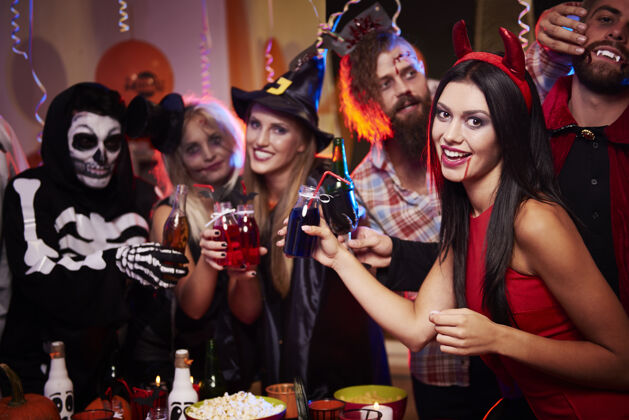 万圣节年轻朋友在万圣节派对上玩得开心酒精桌子女人