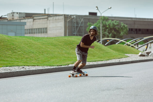 车轮在阳光明媚的日子里 在城市街道上玩滑板的人穿着装备的年轻人在沥青路面上骑行和玩长板休闲活动 运动 极限 爱好和运动的概念极限城市空气