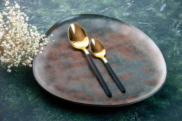 金色前视图深蓝色背景上有金色勺子的棕色盘子勺子厨房晚餐