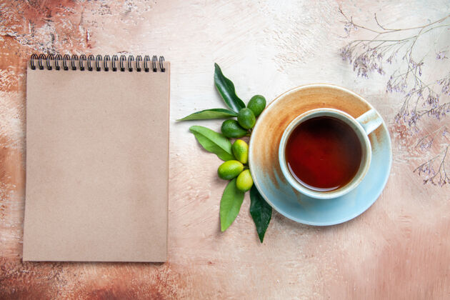 潘趣酒顶部特写镜头一杯茶一杯茶碟上的柑橘类水果奶油笔记本浓缩咖啡奶油
