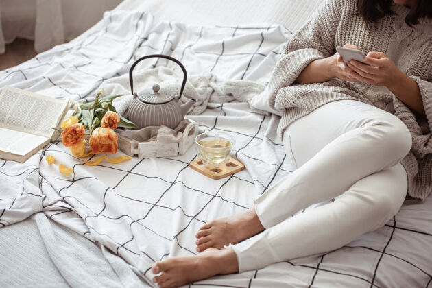 女人一个女人在床上休息 茶 一本书和一束郁金香春天的早晨和周末的概念床茶花