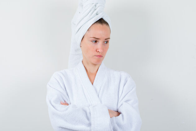 心烦年轻女子交叉双臂站在白色浴衣 毛巾和看起来沮丧 前视图皮肤前面卷发