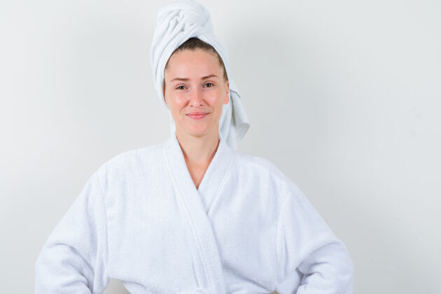 水疗年轻的女士看着相机 穿着白色浴衣 毛巾 看起来很愉快 前视图健康清洁时尚