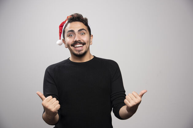 人类微笑着戴着圣诞老人帽子的男人竖起大拇指像手圣诞老人