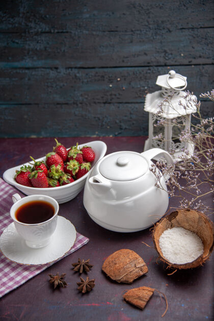 咖啡壶前视一杯茶 用草莓放在深色的茶面上 喝水果色的茶生的杯子早餐