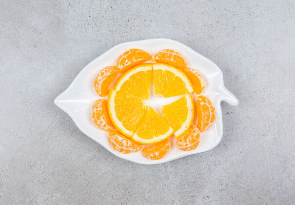 生的橘子和橘子片放在白色盘子里切片柑橘柑橘