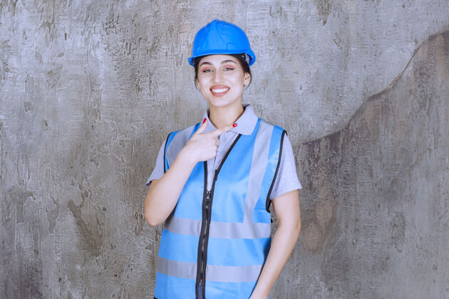 成人女工程师戴着蓝色头盔和装备 在右边展示着什么东西年轻人方向人员