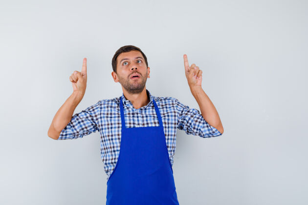 男士穿着蓝色围裙和衬衫的年轻男厨师烹饪成人男士