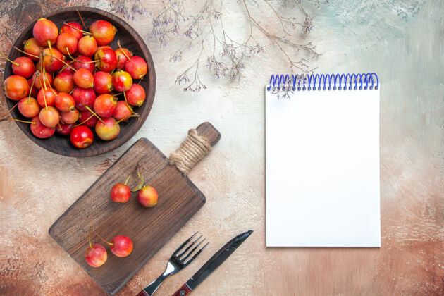 食物俯视樱桃浆果板碗上的樱桃叉刀白色笔记本西红柿黑板顶部