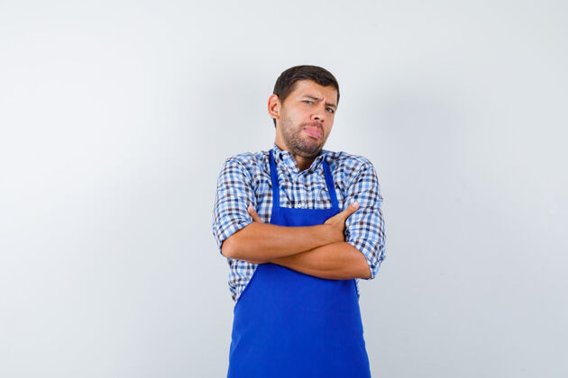 烹饪穿着蓝色围裙和衬衫的年轻男厨师年轻男士男士
