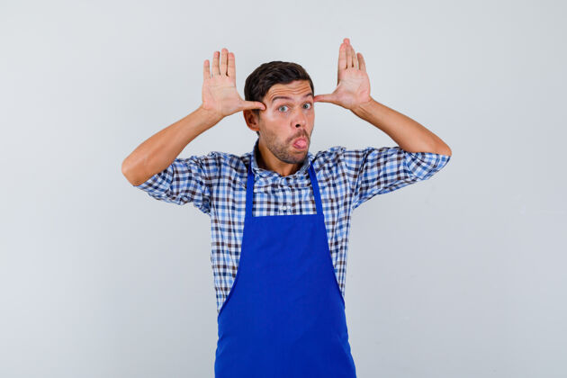 烹饪穿着蓝色围裙和衬衫的年轻男厨师男士制服年轻