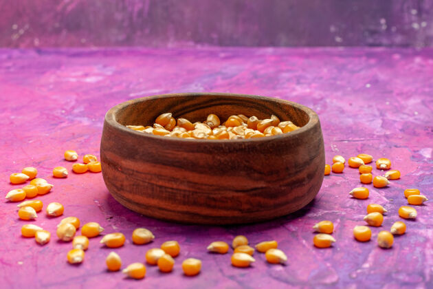 碗前视图生玉米内盘上粉红色桌上玉米色爆米花健康玉米生玉米