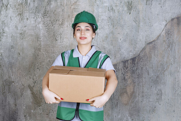 制服戴绿帽的女工程师手里拿着一个纸板箱雇员成人纸箱
